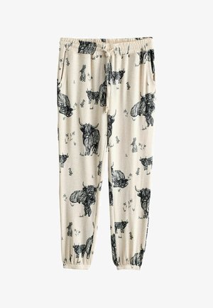 Joggers en coton beige clair avec illustrations animales noires, comprenant des vaches et des lapins, avec une taille élastique et des chevilles resserrées.