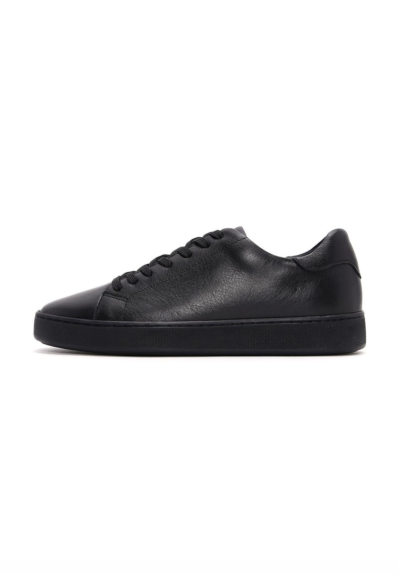 Zapatilla negra de cuero con una textura suave, punta redondeada y suela de goma plana. Cuenta con cierre de cordones y un diseño minimalista.