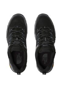 Czarne buty do wędrówek wykonane z materiałów siatkowych i syntetycznych; posiadają wyściełany kołnierz, teksturowany język oraz charakterystyczne żółte logo na pięcie.