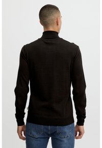 Fekete, slim-fit garbónyakú pulóver hosszú ujjal, bordázott mandzsettákkal és szegéllyel. Az anyag textúrája simának tűnik. A hátsó nézeten a vállvarrások láthatók.