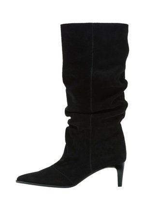 Botte mi-mollet en daim noir avec un bout pointu et une tige tombante, dotée d’un talon fin et effilé type kitten heel.