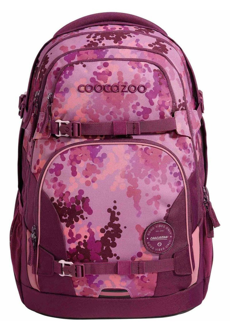 Backpack with a purple camouflage pattern, featuring various shades of pink and violet, fabric material, multiple zippered compartments, and adjustable straps.
