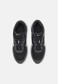 Scarpe sportive nere con parte superiore in mesh e accenti grigi; presentano lacci rotondi e un logo Nike bianco sui lati e sulla linguetta.