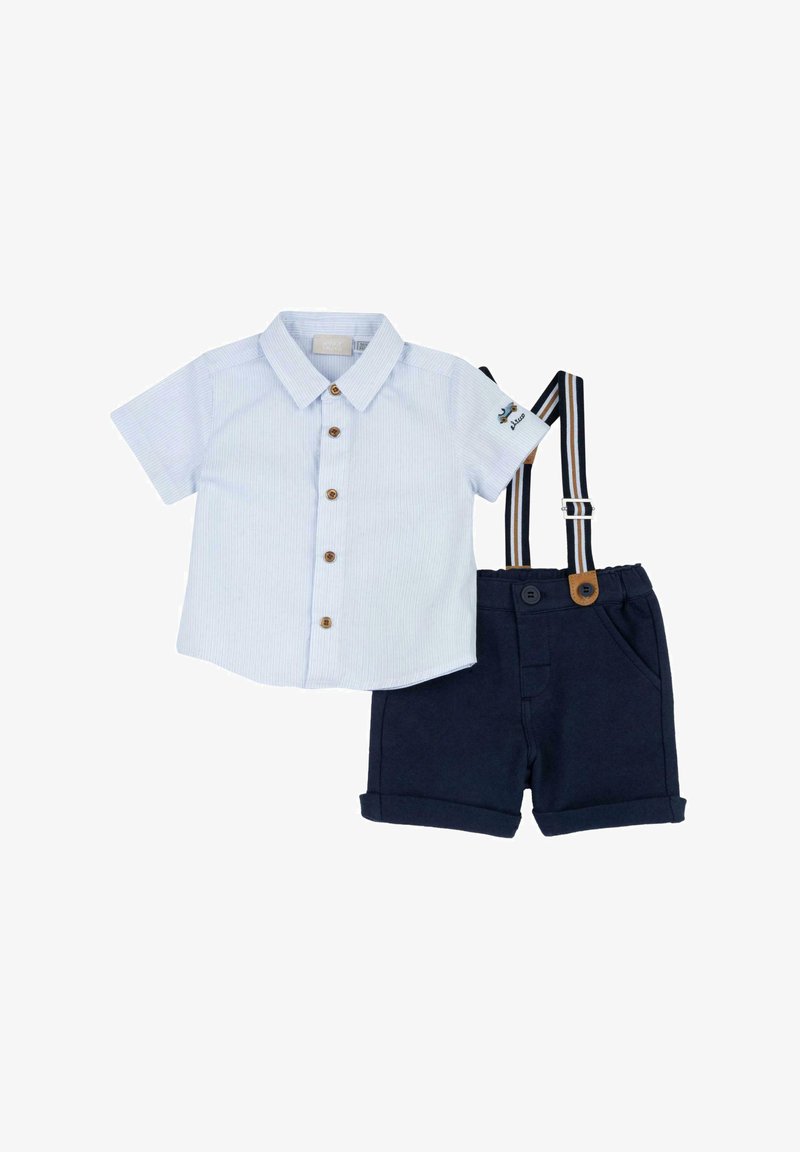 Camicia a maniche corte a strisce azzurre, con bottoni di legno, abbinata a pantaloni corti blu navy con risvolti e bretelle regolabili.