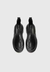Zwarte leren enkellaarzen met een gladde afwerking, elastische zijkanten, ronde neus en dikke rubberen zool. Minimalistisch ontwerp zonder patronen.
