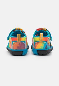 Pisane otroške čevlje z vzorcem mavrične tie-dye, mrežastimi stranicami, mehkim tekstilnim podplatom in črnimi gumijastimi podplati. Prilagodljive pete.