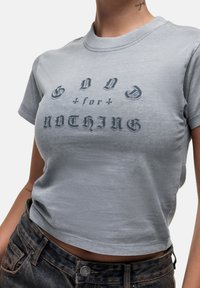 T-shirt corta in cotone grigio con stampa nera "GOD for NOTHING" in diversi stili di carattere, maniche corte e scollatura rotonda.