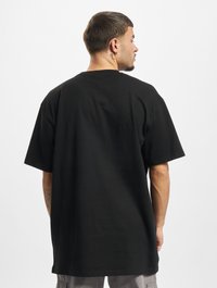 Sort oversized t-shirt lavet af bomuld, med korte ærmer og rund hals. Bagsiden har ingen grafik eller udsmykninger.