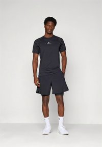 Svart atletisk skjorte og shorts laget av lett materiale. Har en liten, hvit Nike-logo på både skjorten og shortsen.