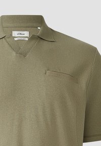 Olijfgroen polo met korte mouwen, uitgevoerd in een ribbelstructuur, met een V-hals en een klein borstzakje. Gemaakt van een katoen-linnen mix.