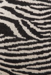 Gros plan sur un tissu tricoté présentant un motif à rayures zébrées noires et blanches floues.