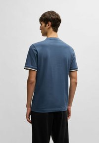 Blå kortärmad t-shirt i bomullsblandning med rund halsringning, med kontrasterande randiga detaljer på ärmarna och rak skärning.