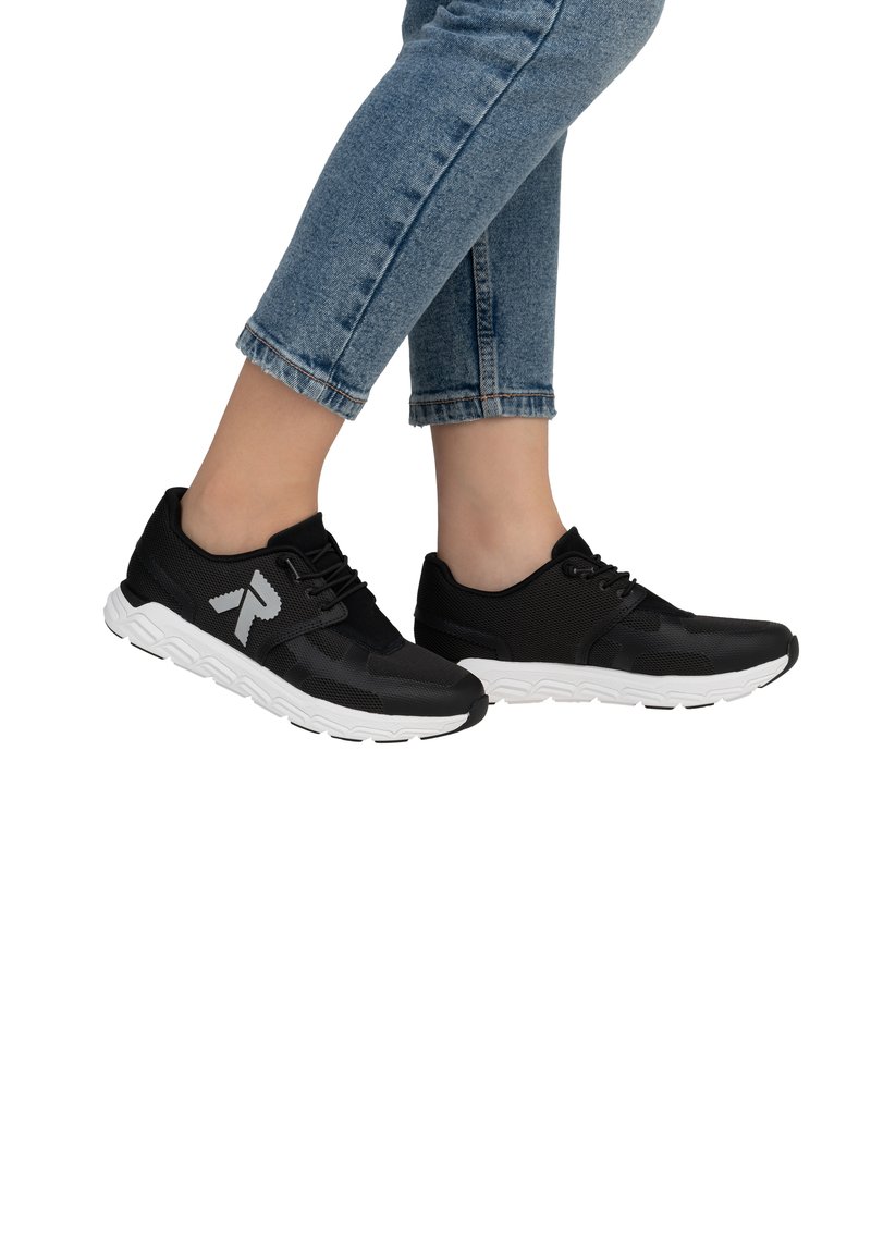 Black athletic shoes with a mesh upper, white sole, and contrasting logo. Worn with cropped blue denim jeans.