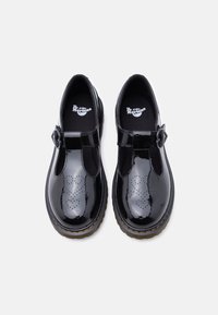 Chaussures Mary Jane en cuir verni noir avec un bout rond, des détails perforés, une bride ajustable et une semelle extérieure épaisse et texturée.