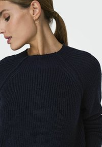 Grobstrick-Pullover in dunkelblau mit gerippter Textur, ausgestattet mit einem Rundhalsausschnitt und Raglanärmeln. Abgeschlossen mit dezenten Nahtdetails.