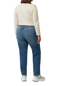 Blauwe denim jeans met een rechte pasvorm, voorzien van achterzakken en een mid-rise tailleband. Gecombineerd met een beige gestreept shirt met lange mouwen.