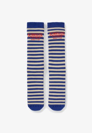 Chaussettes hautes jusqu'aux genoux à rayures bleu et crème avec le texte rouge "Stranger Things Benetton" en haut sur fond blanc.