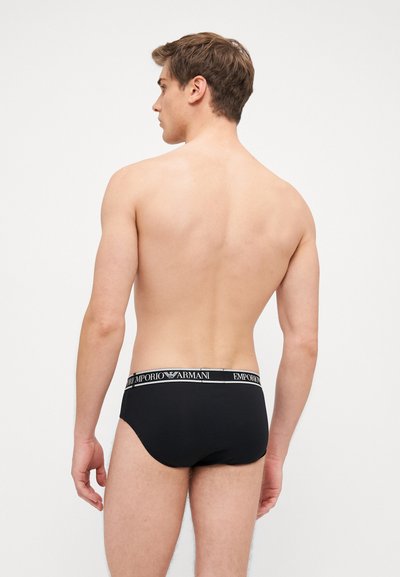 Slips neri da uomo con texture uniforme, dotati di una cintura elastica con il marchio "EMPORIO ARMANI" in lettere bianche.