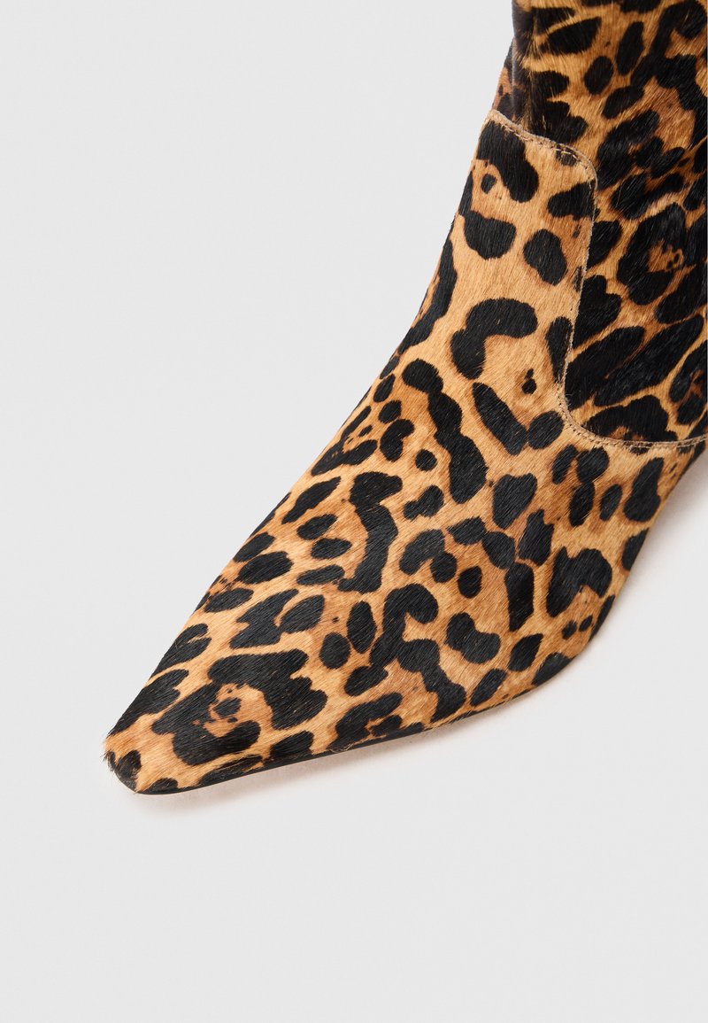 Stivaletto alla caviglia con stampa leopardata e punta affusolata, caratterizzato da una texture morbida, motivi marroni e neri, e pannelli laterali elastici.