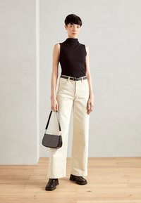Must have mustrindlane turtleneck top, valge laiad püksid, must rihm, tekstureeritud must käekott ja jämedad mustad platvormiglad.