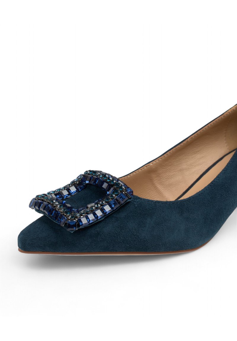 Scarpa a punta in suede verde scuro con una fibbia rettangolare gioiello che presenta pietre blu e nere sul davanti. Fodera interna liscia.