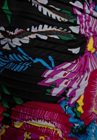 Abito multicolore con motivi floreali vivaci e tessuto plissettato nero, comprendente tonalità di rosa, blu, verde e accenti gialli.