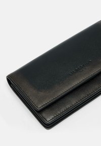 Portefeuille en cuir noir avec une texture lisse, de forme rectangulaire, logo embossé et un éclat subtil, featuring des coutures minimales le long des bords.