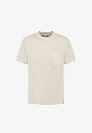 Kortærmet t-shirt med rund hals i lys beige, lavet af blødt stof med en enkelt lomme detalje på venstre bryst. Enkel og glat tekstur.