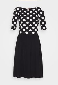 Musta mekko valkoisilla pilkuilla. Lyhyet hihat, pyöreä pääntie, vartalonmyötäinen yläosa ja levenevä hame, jossa on joustava vyötärö. Pehmeä kangaspinta.