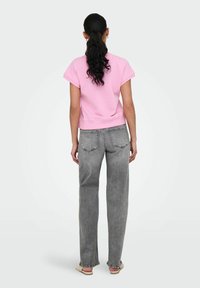 Roze sweatshirt met korte mouwen, gecombineerd met grijze rechte spijkerbroek. De spijkerbroek heeft een klassieke vijf-pocketontwerp met subtiele stikseldetails.