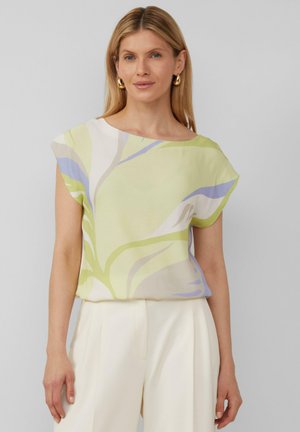 Bloes met korte mouwen in een lichtgroene kleur met een bloemenpatroon, voorzien van zachte blauwe en witte accenten. Het materiaal lijkt lichtgewicht en heeft een gladde textuur.