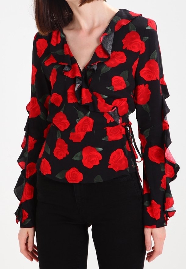 Blusa nera con maniche a volant e stampa di rose rosse, dotata di design avvolgente e laccetti laterali regolabili. Texture del tessuto liscia.