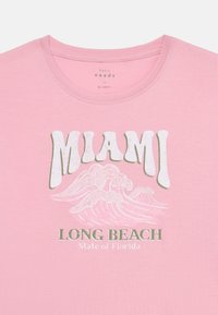Růžové bavlněné tričko s retro bílou grafikou "MIAMI", designem vln a textem "LONG BEACH State of Florida" v zelené barvě. Kulatý výstřih.