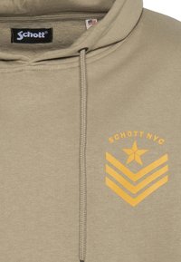 Bluza z kapturem w kolorze khaki z regulowanym sznurkiem, ozdobiona żółtą grafiką gwiazdy z wstążkami w kształcie litery V. Wykonana z miękkiego, teksturowanego materiału.