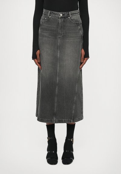 Denim midi-nederdel i mørkegrå, med en lige skæring, frontsømme og bæltesløjfer. Kombineret med sorte strømper og sko med spænder.