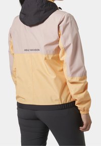 Lättviktsjacka med färgblockering som har en svart huva, rosa och gula paneler, elastiska ärmslut och dragsko i nederkant. Logotyp på baksidan.