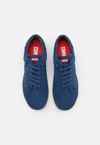 Sneakers in tela blu con punta rotonda, design con lacci e logo rosso "CAMPER" sulle sole interne. Suola texturizzata e dettagli di cucitura.