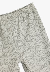 Grå pyjamasbukser med elastisk talje, prydet med et gentaget "LOVE" print i en skinnende sølvtekstur. Designet til komfort og afslappet brug.