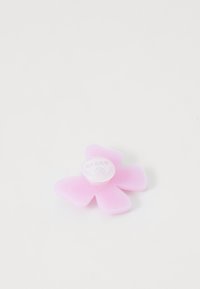 A pink flower-shaped charm with rounded petals and a white circular center labeled “CROCS,” placed on a plain white background.