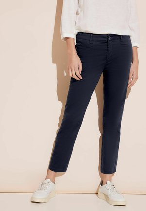 Pantaloni slim-fit blu navy realizzati in cotone misto, con un design classico, cinque tasche e chiusura con bottone, abbinati a sneaker bianche.