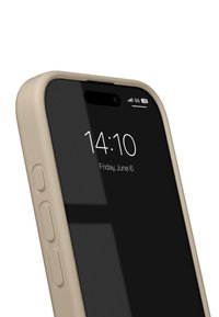 Beige telefoncover omkring en sort skærm, der viser klokkeslæt og dato. Sideknapper synlige med en glat overflade og afrundede kanter.