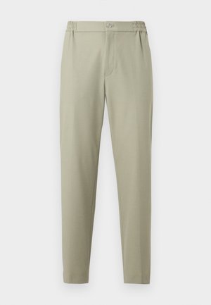 Beige innsnevrede bukser med elastisk midjebånd, knappelukking og frontglidelås, vist på hvit, jevn bakgrunn.