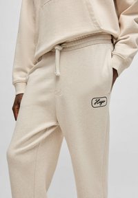 Beige joggingbroek van zachte stof met een elastische tailleband, zijzakken en een geborduurd "Hugo" logo op de linker dij.