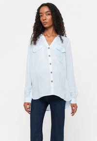 Light blue striped shirt with a V-neck, long sleeves, two pockets, and gold buttons. The fabric appears lightweight and slightly translucent.