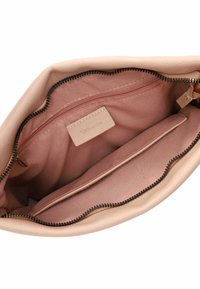 Interno di una borsa in pelle rosa con una texture liscia. Presenta una tasca con zip, una tasca a scomparsa e un rivestimento in tessuto contrapposto. Chiusura con zip.