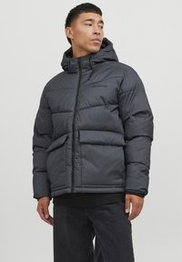 Mørk grå pufferjakke med hætte, der har lynlåslukning, forlommer og en let glans. Tekstureret stof med et quiltet design.