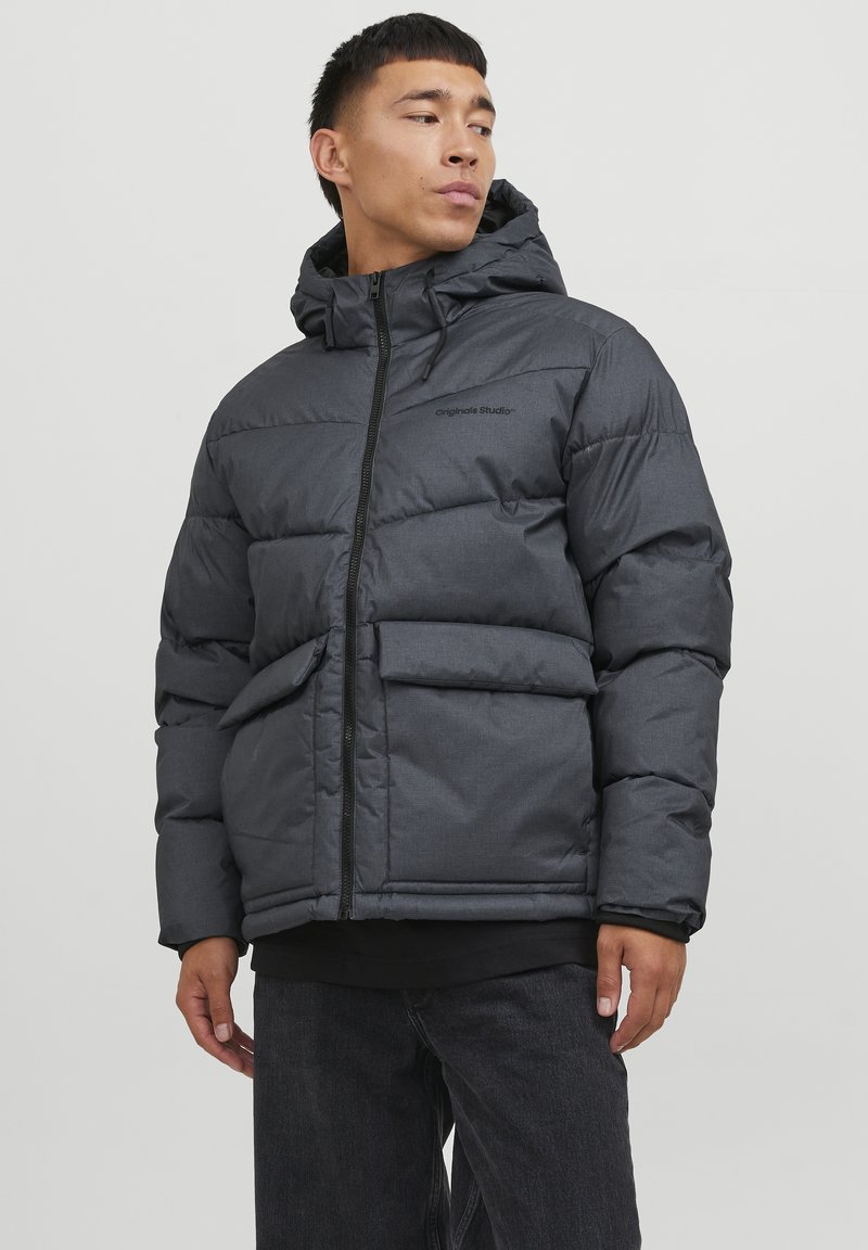 Mørk grå pufferjakke med hætte, der har lynlåslukning, forlommer og en let glans. Tekstureret stof med et quiltet design.
