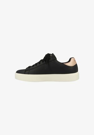 Zapatilla de cuero negra con puntera redondeada, suela blanca, cordones negros y un acento metálico en rosa dorado en el talón. Textura suave en general.