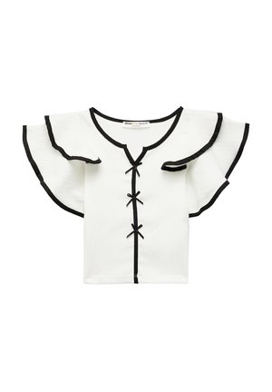 Top bianco a maniche corte con bordi neri, scollo a V e maniche a volant. Presenta fiocchi neri decorativi lungo il centro. Tessuto texturizzato.