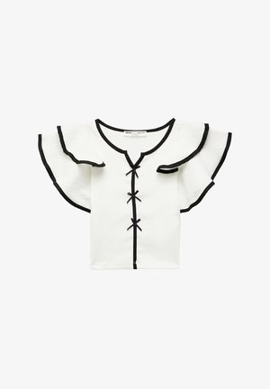 Witte top met korte mouwen en zwarte accenten, V-hals en ruches aan de mouwen. Bevat decoratieve zwarte strikjes langs het midden. Geribbelde stof.